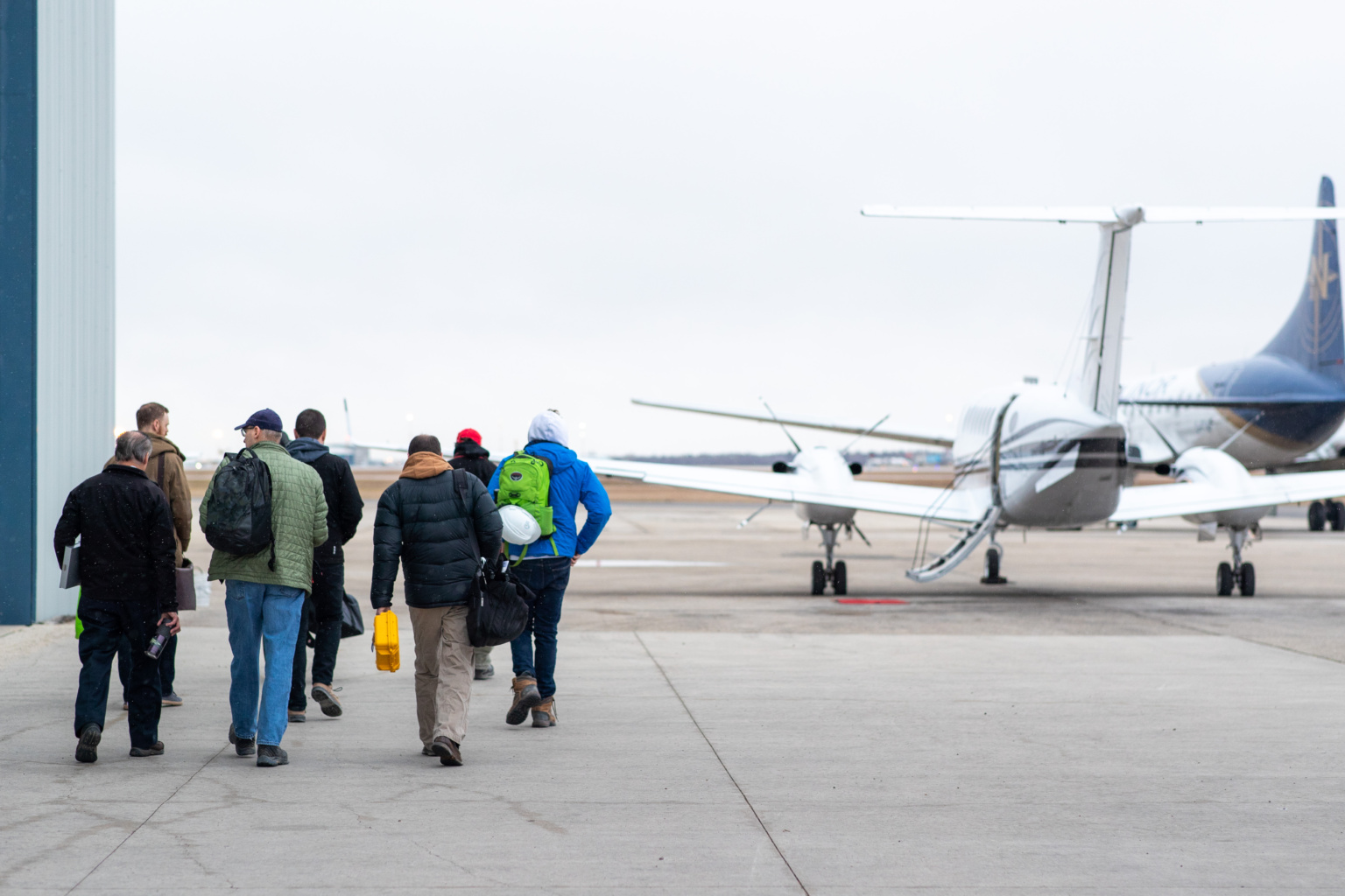Passengers walking toward a plane to board on the tarmac.